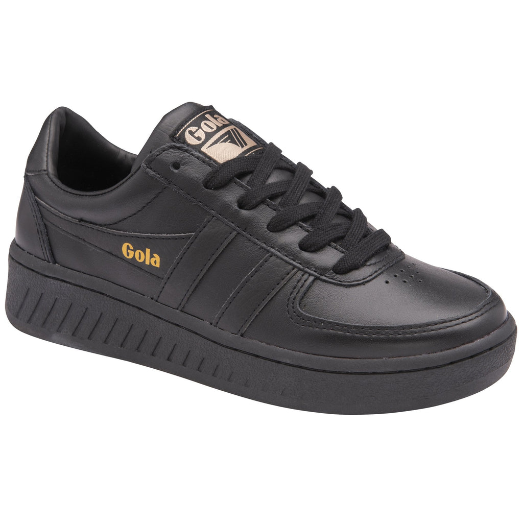 A black Gola trainer with a gold logo on the side and tongue, angled view.