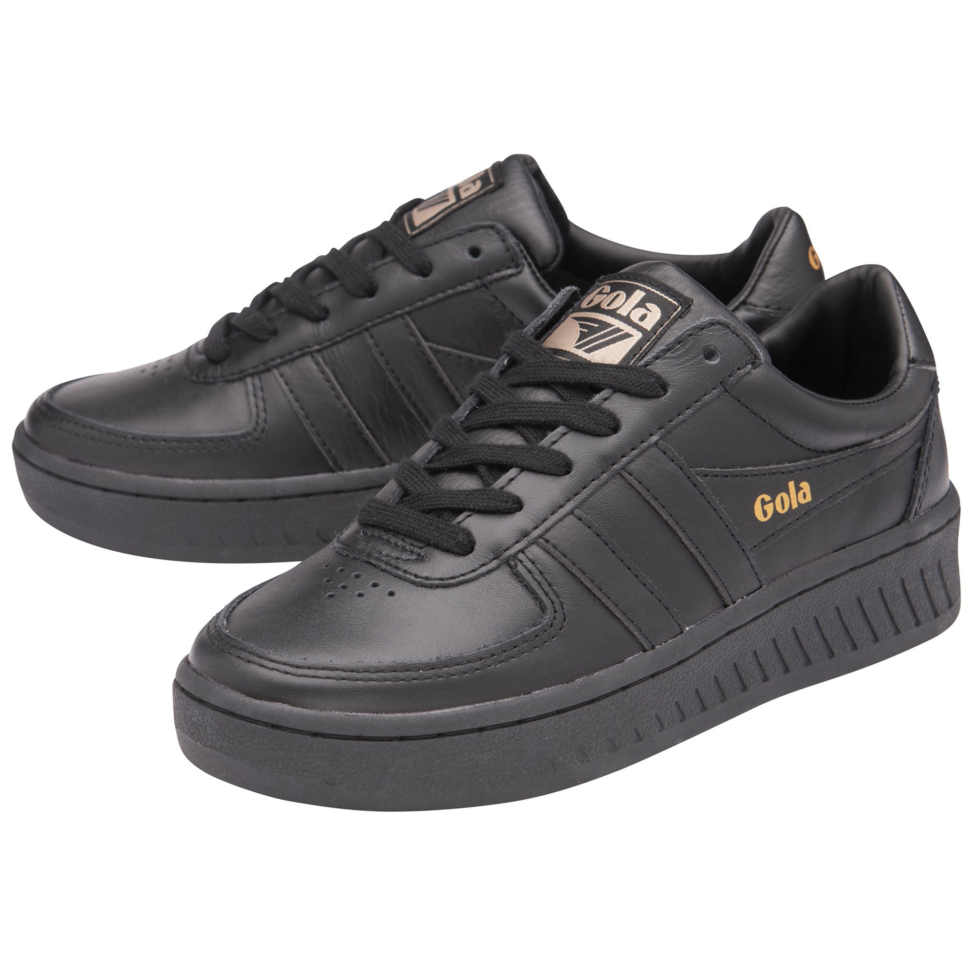 A pair of black Gola trainers with gold logos on the side and tongue, angled.