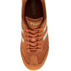 The top-down view of a single orange Gola Harrier trainer with white stripes and laces.