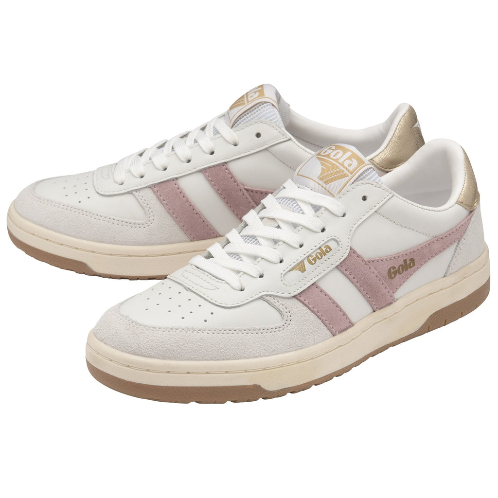 A pair of white trainers with pink stripes and gold heel tabs are presented from an angle.