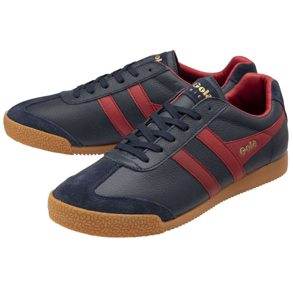 A pair of Gola low-top sneakers in navy with red stripes and gum soles, angled together.