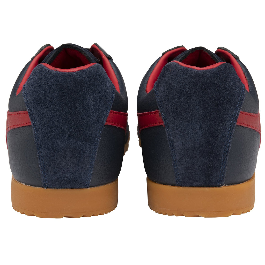A pair of Gola low-top sneakers in navy with red stripes and gum soles, viewed from the back.