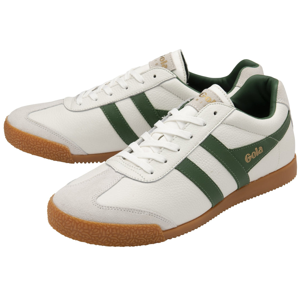 A pair of white Gola Harrier trainers with green stripes and gum soles, viewed from an angle.