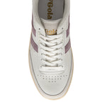 The front of a white sneaker with white laces and purple stripes on the side.