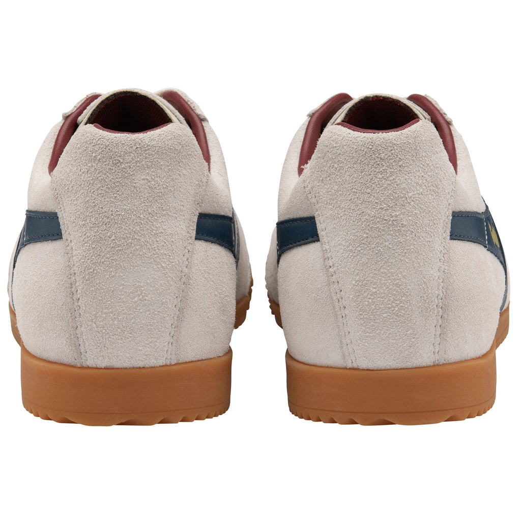 The rear view of a pair of off-white Gola Harrier trainers with navy stripes.