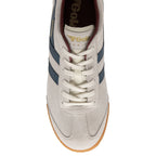 A top-down view of an off-white Gola Harrier trainer with navy stripes and cream laces.