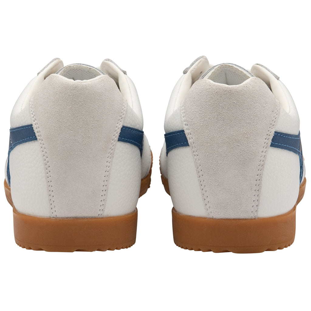 The backs of a pair of white Gola Harrier shoes with blue stripes.
