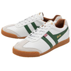 A pair of white Gola Harrier trainers with green stripes, isolated on a white background.