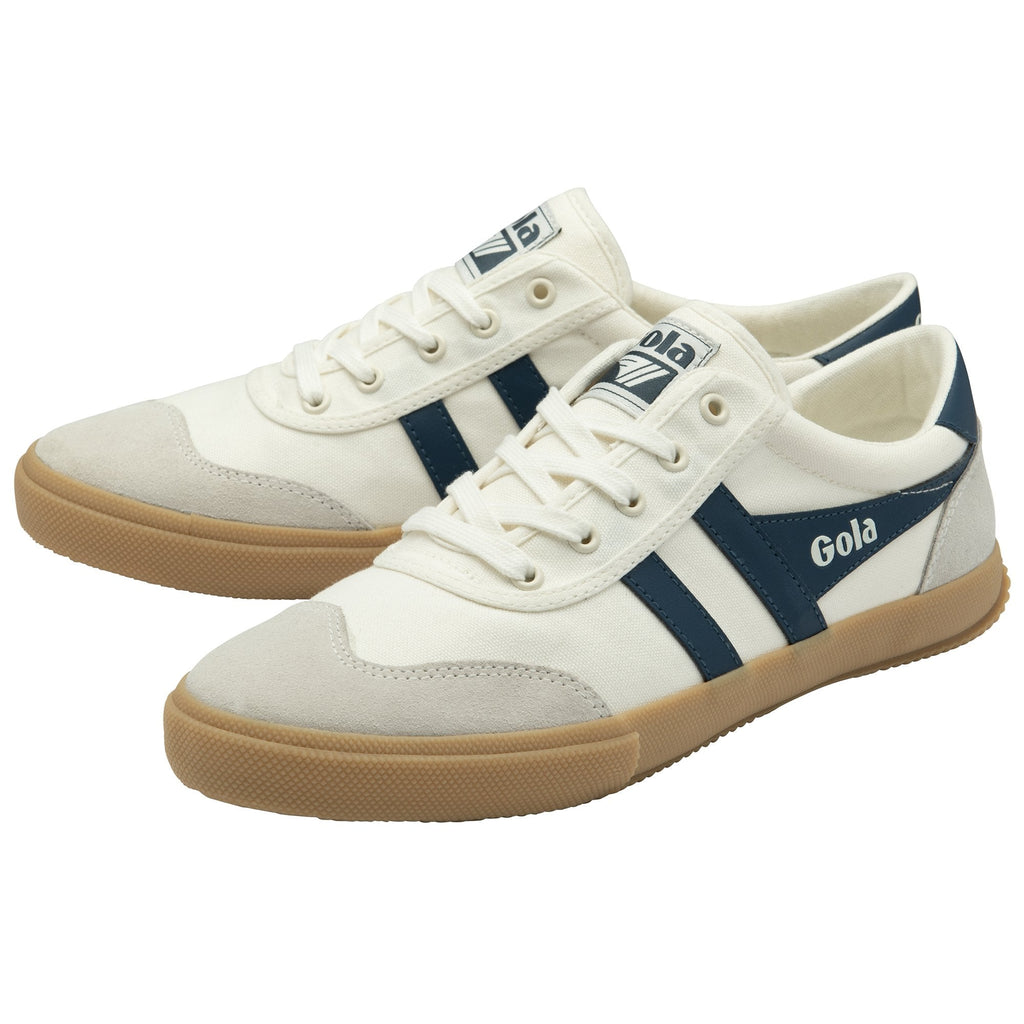 A pair of white Gola sneakers with navy blue stripes, light grey suede, and gum soles.