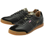 A pair of Gola low-top trainers in black with gum soles, angled for a dynamic view.