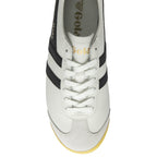An overhead view of a white Gola sneaker with black stripes and white laces.