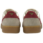 Rear view of two sneakers, light brown suede with red heel accents and a gold logo, gum soles