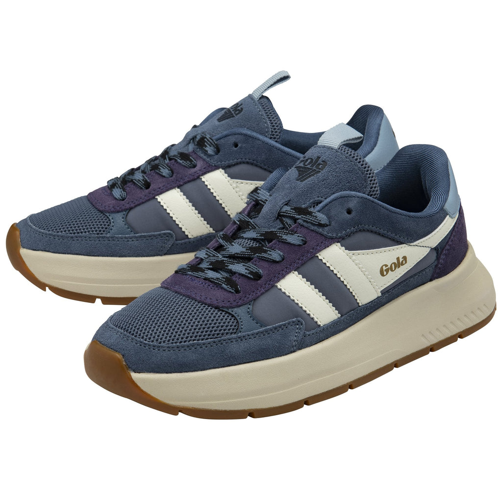 A pair of Gola women's trainers, viewed from a high angle, with a navy upper, white stripes, and tan soles.