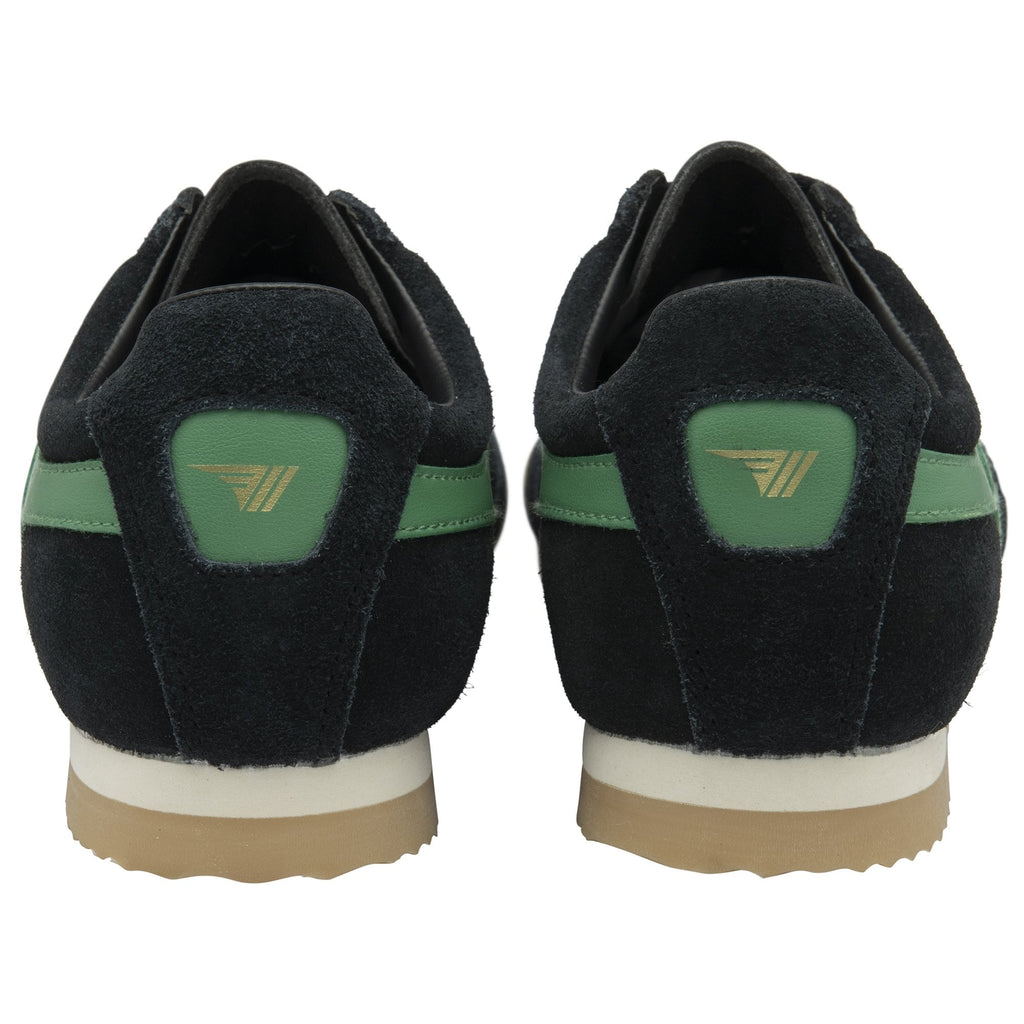 The back view of a pair of black sneakers with green accents and light brown soles.