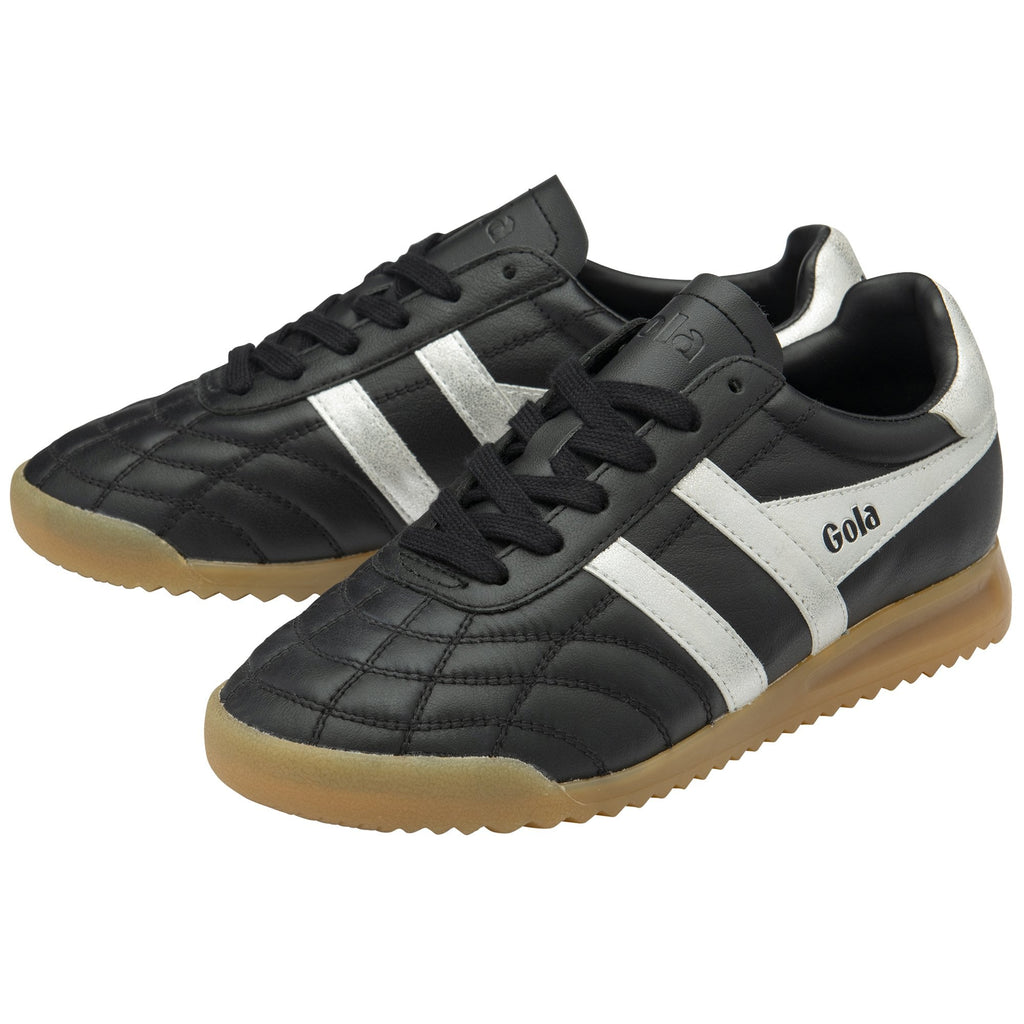 A pair of Gola low-top indoor soccer shoes in black and white with gum soles, front view.
