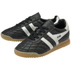 A pair of Gola low-top indoor soccer shoes in black and white with gum soles, front view.