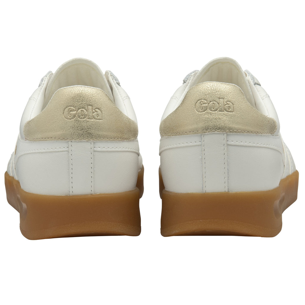 The backs of two white and gold Gola sneakers with gum soles, showing the logo.