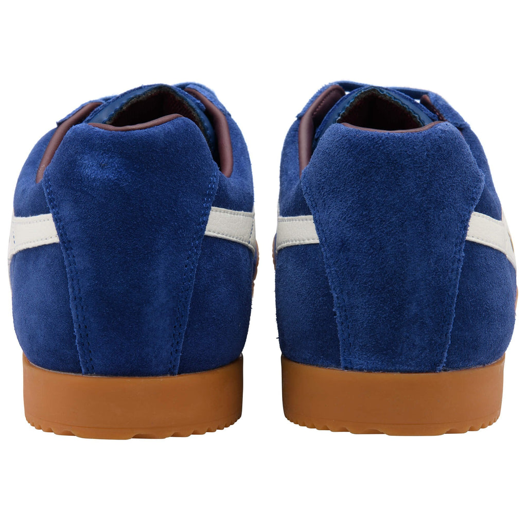 Blue suede trainers with white stripes and brown soles on a white background