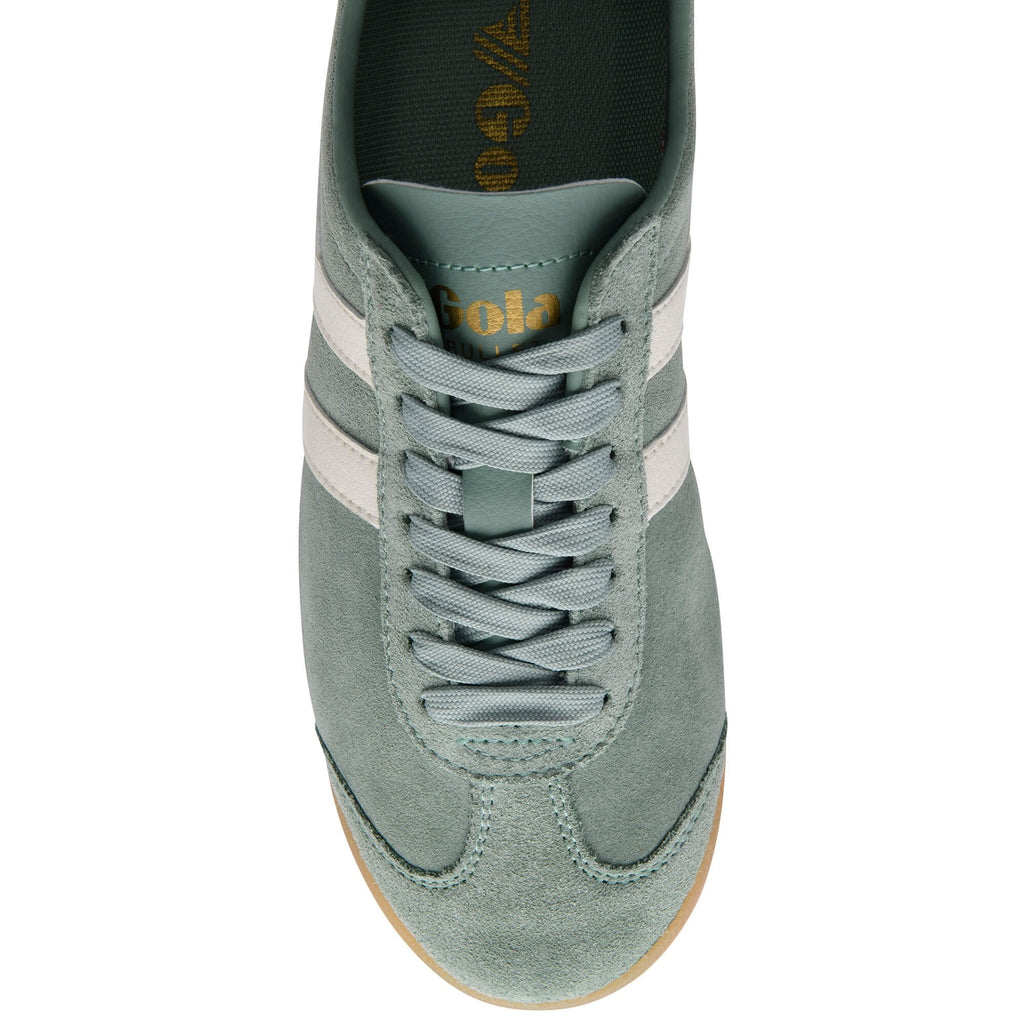 Close up of a Gola trainer in green suede with white stripes and laces on a white background