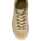 Gold trainer with white laces on a white background