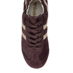 Top-down view of a burgundy suede trainer with beige stripes and laces
