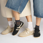Two pairs of Gola Classics trainers in black and beige suede worn with patterned socks
