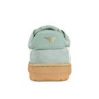 Rear view of a sage green suede trainer with a gum rubber sole and gold logo on the heel tab