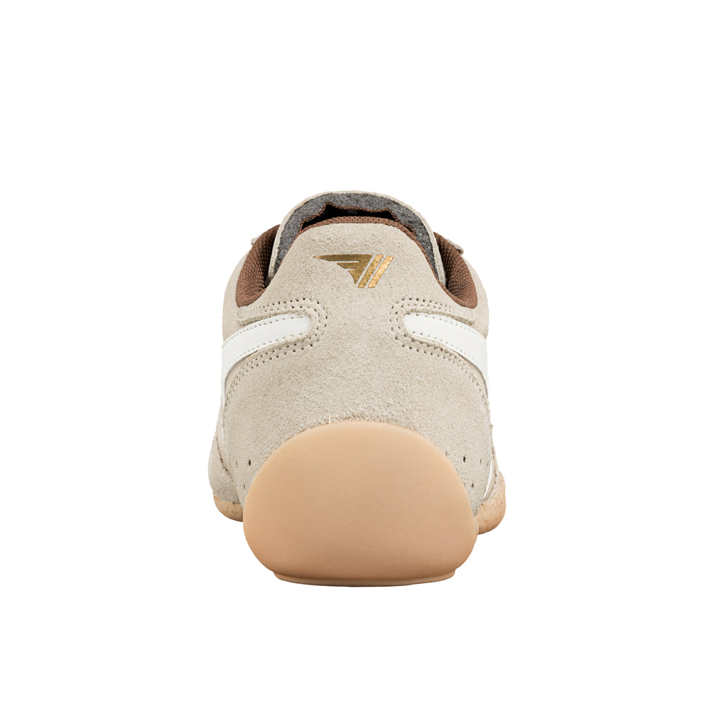 Rear view of a beige suede trainer with a gum rubber heel and gold logo on the heel tab