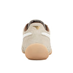 Rear view of a beige suede trainer with a gum rubber heel and gold logo on the heel tab