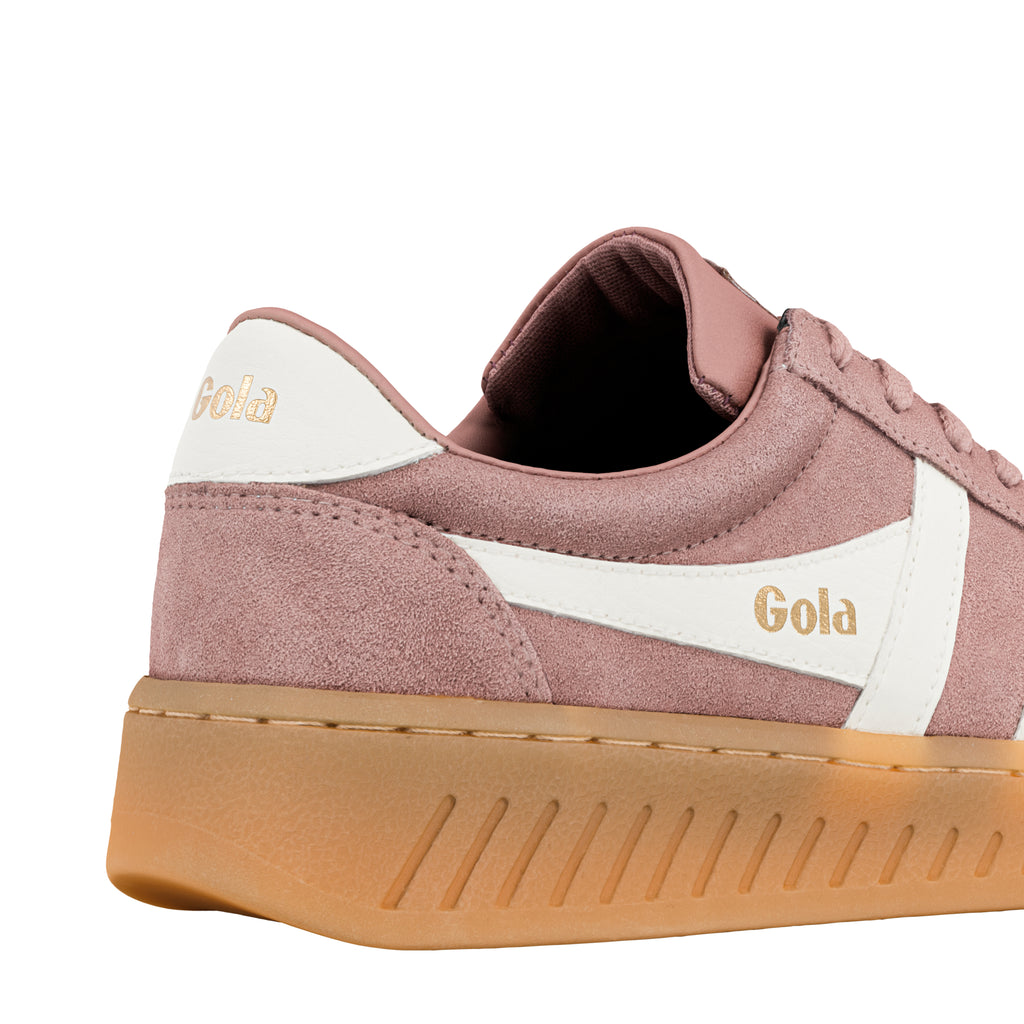 Close up of the heel and side of a pink suede Gola trainer with a white stripe and gum sole