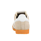 Rear view of a beige suede trainer with a white heel tab and orange rubber sole