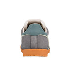 Rear view of a grey suede trainer with a teal heel tab and orange rubber sole