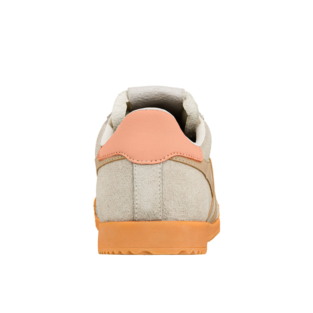 Rear view of a beige suede trainer with a peach heel tab and orange rubber sole