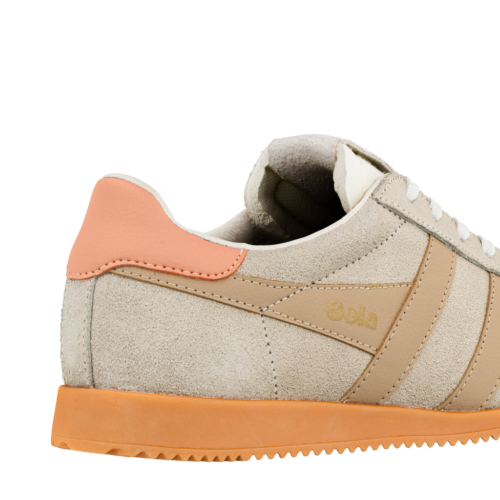 Close up of the heel and side panel of a beige suede Gola trainer with a peach heel tab and orange sole