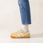 Gola Classics yellow suede trainers with white stripes worn with blue jeans and white socks