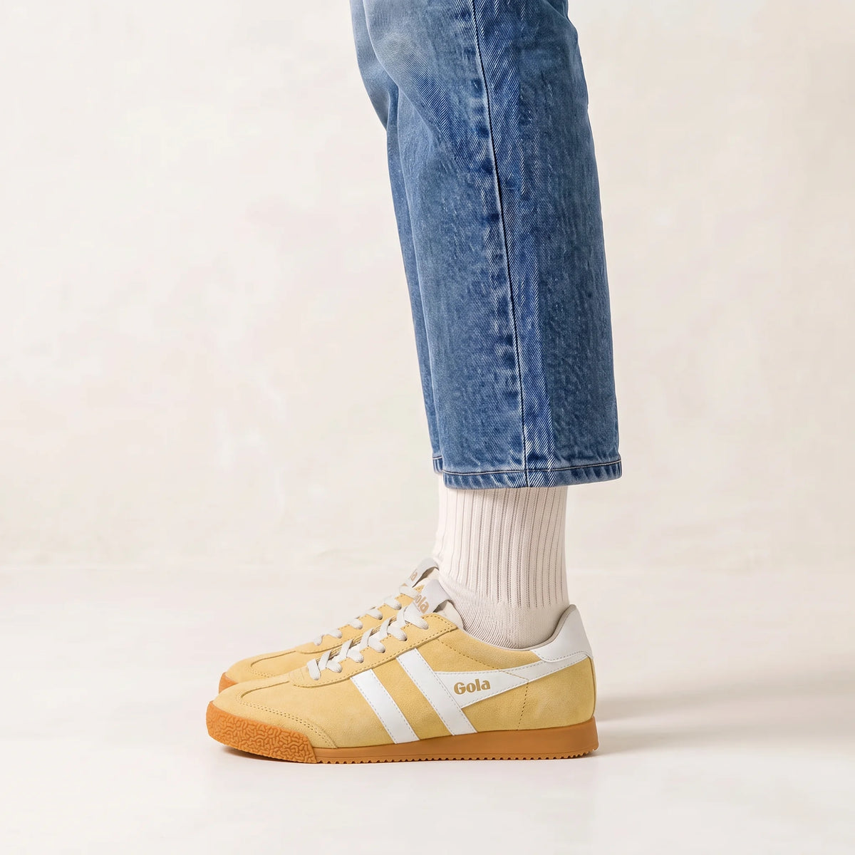 Gola Classics yellow suede trainers with white stripes worn with blue jeans and white socks