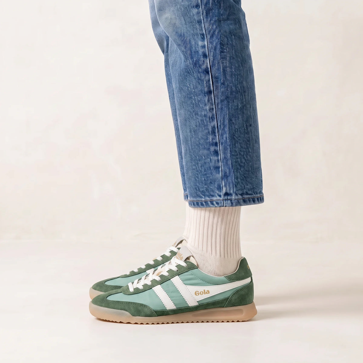 Gola Classics green and white trainers with gum sole worn with blue jeans and white socks