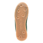 Underside of a green trainer with a light brown sole, featuring a wavy pattern and circular grips