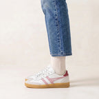 Gola Classics white trainers with pink side stripes and gum sole worn with blue jeans and cream socks