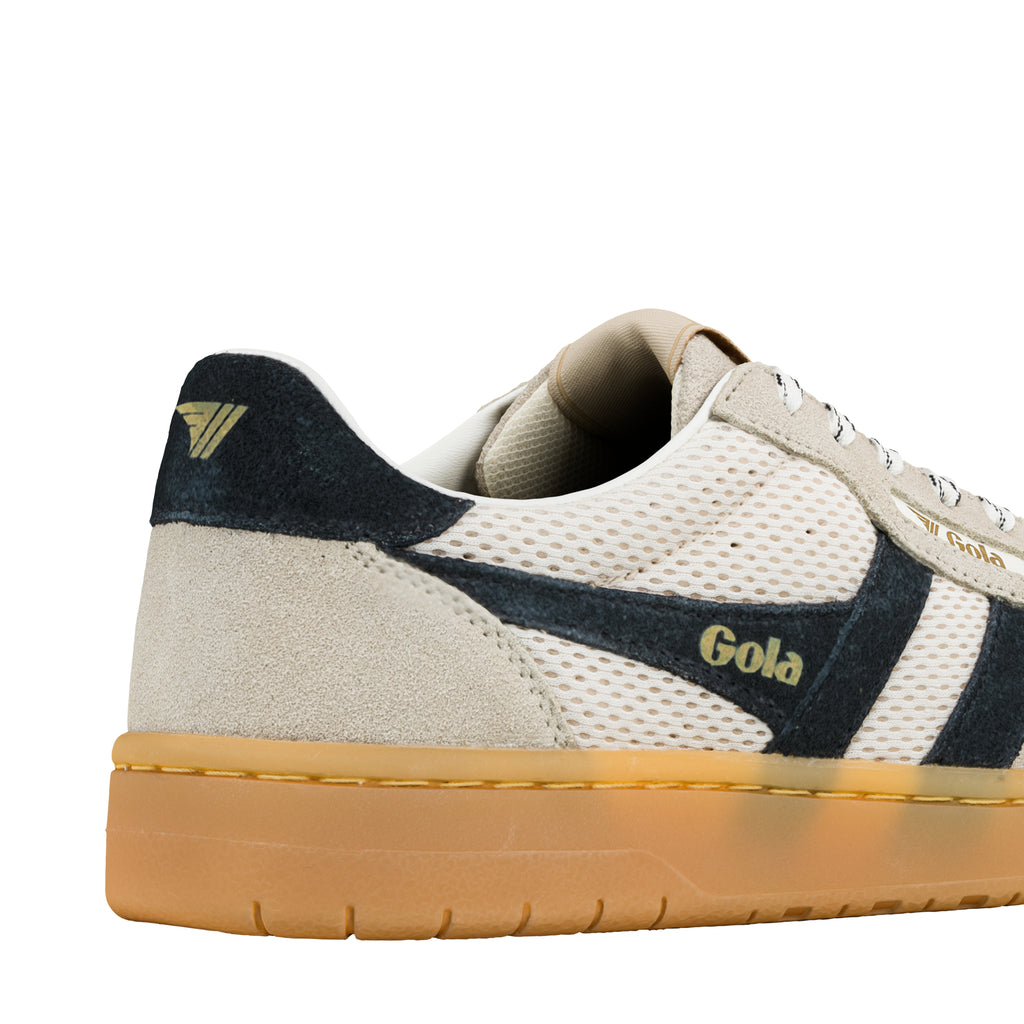 Close up of the heel and side panel of a cream and navy Gola trainer with a gum sole
