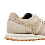 Close up of the heel and side panel of a beige Gola trainer with gold branding