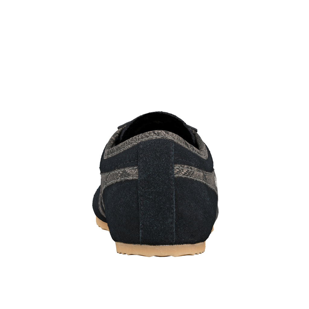 Rear view of a navy blue suede trainer with grey textured detailing and a gum rubber sole