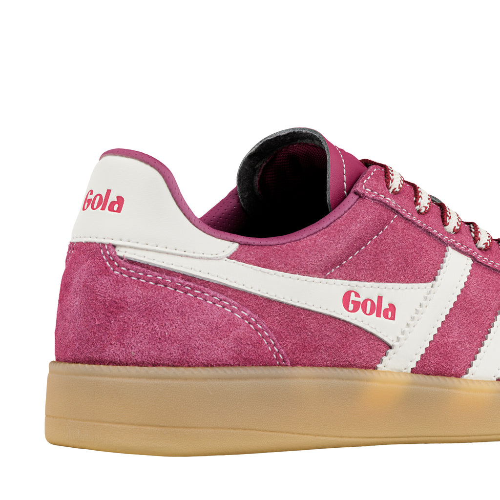 Close up of a pink suede Gola trainer with white side stripes and a gum rubber sole