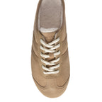 Top-down view of a beige suede trainer with white laces and a cream fleece lining