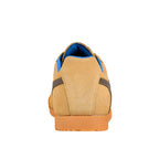 Rear view of a tan suede trainer with a blue inner lining and orange rubber sole