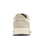 Rear view of a beige suede trainer with a cream midsole and black rubber outsole