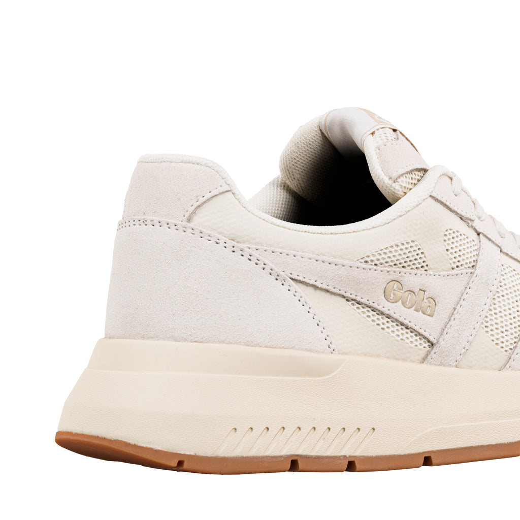 Close up of the heel and side of a cream Gola trainer with mesh panels and a gum rubber sole