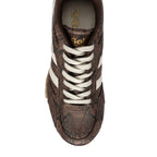 Close-up top view of a brown Gola trainer with a snakeskin pattern, white laces, and white side stripes