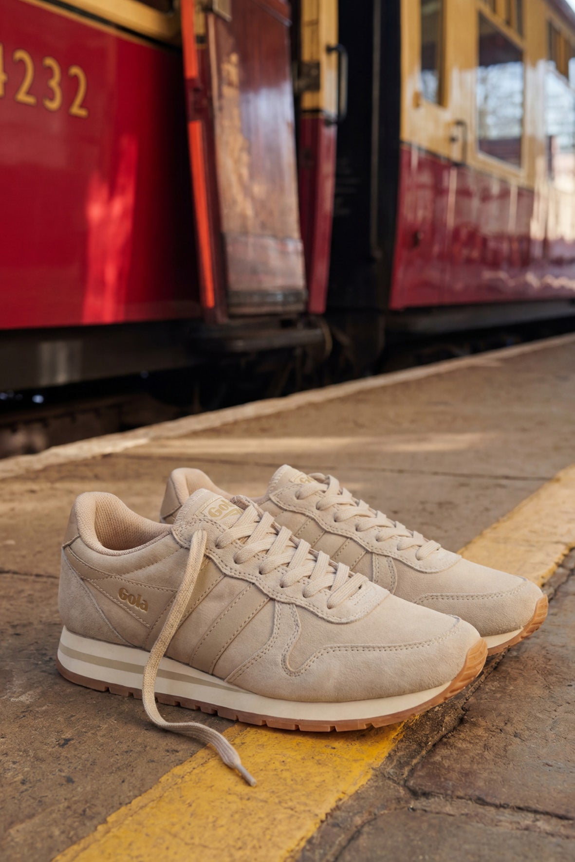 Pair of Gola sneakers in beige suede and mesh with gum sole on a train platform