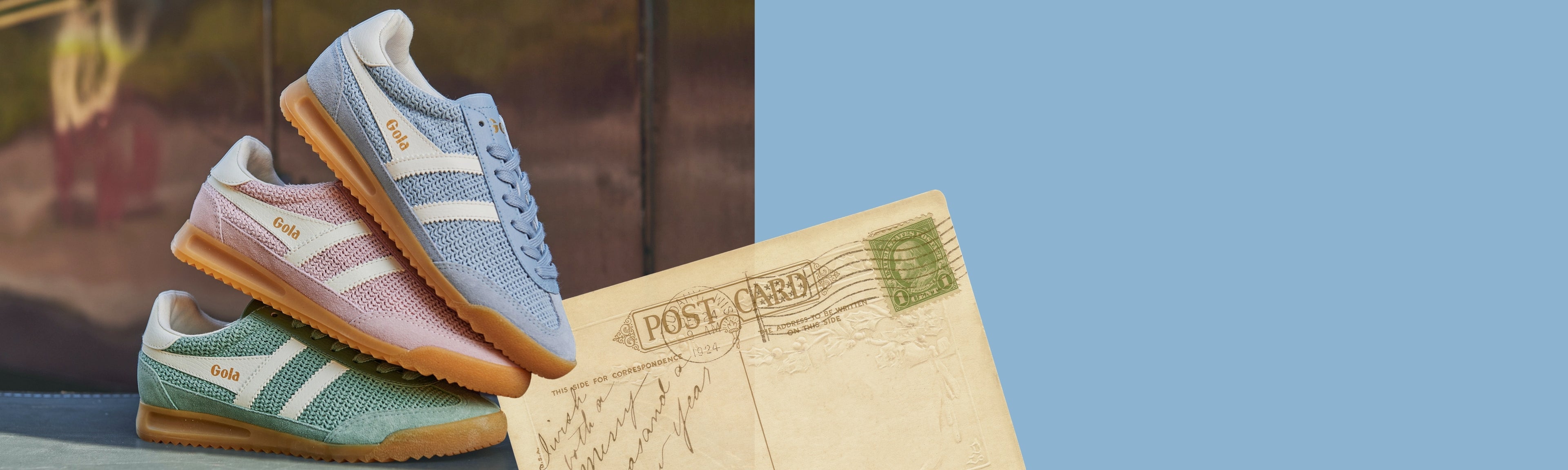 Three Gola trainers in blue, pink, and green, stacked next to a vintage postcard